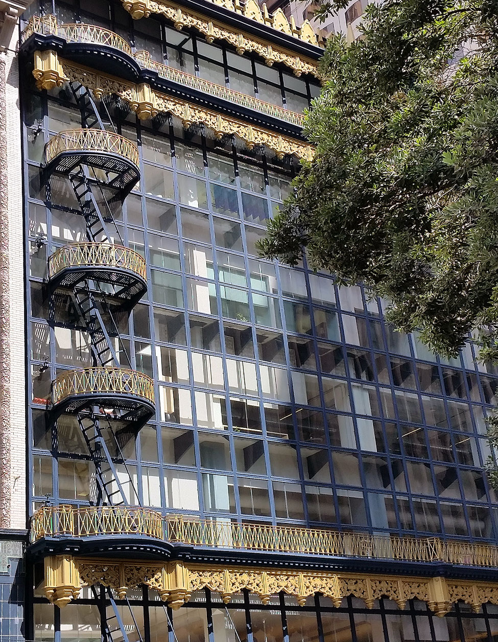 Street-level view of Hallidie Building, showing ornamented fire escapes.