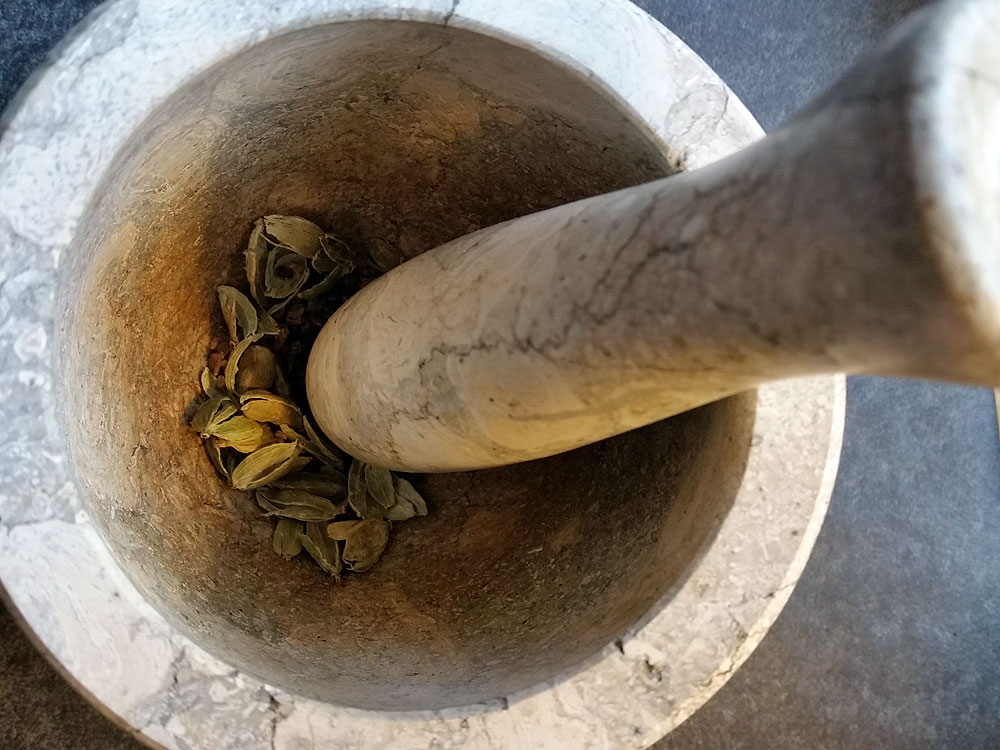 I grind the ingredients (here cardamom pods) with a mortar and pestle.